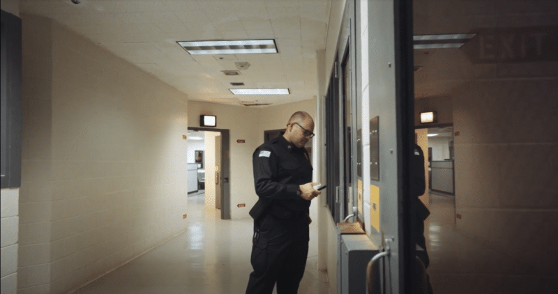 Corrections officer using mobile device inside jail