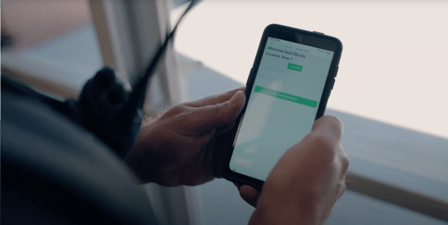 Hands of school resource officer holding mobile device using Life Check Systems security technology